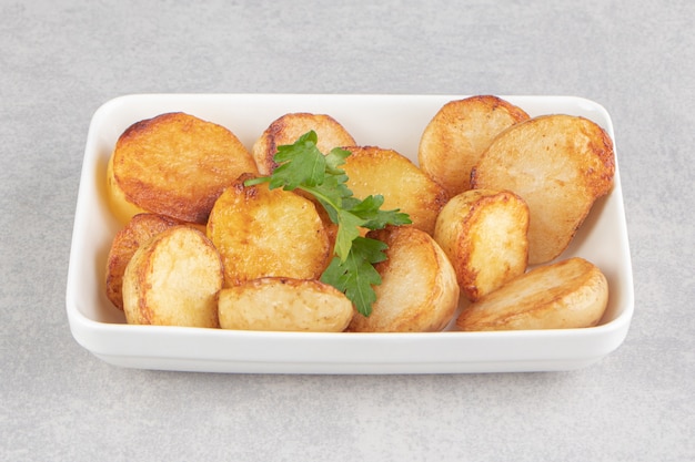 Кусочки жареного картофеля на белой тарелке.