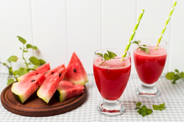 Slices of fruits on board and glasses with cocktail on napkin