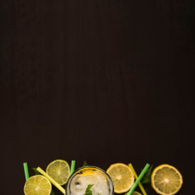 Slices of fruits near glass with ice