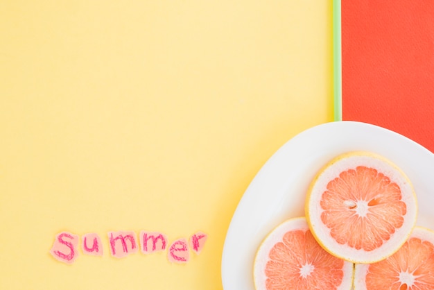 Free photo slices of fruits on plate near summer word