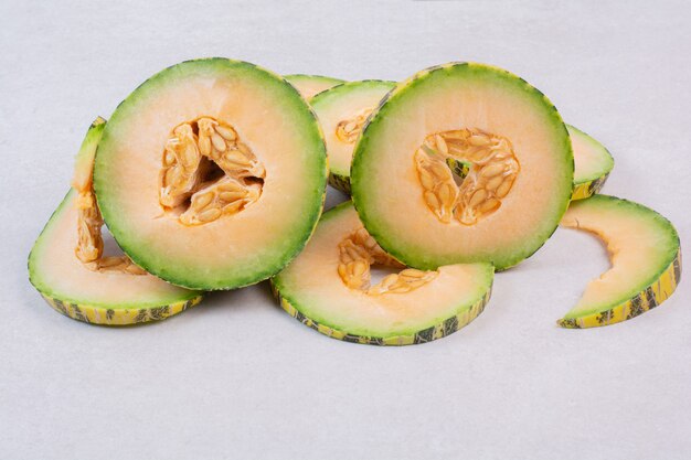 Slices of green melon on white.