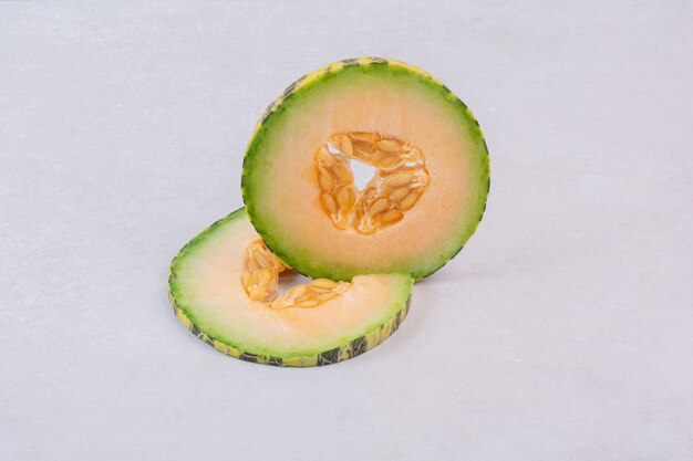 Slices of green melon on white.