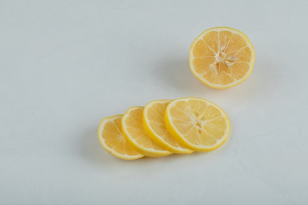 Fette di limone succoso su una superficie bianca.