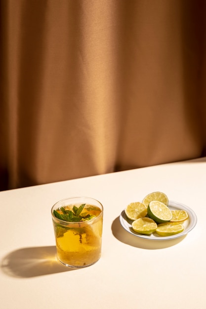 Ломтики лимона с коктейлем на белом столе