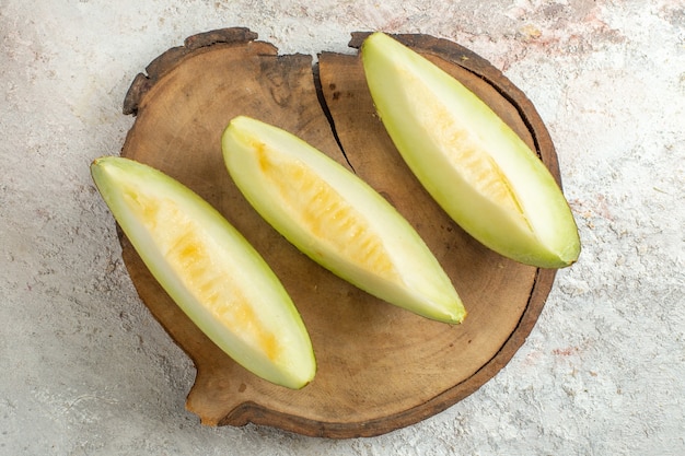 Slices of melon on wooden platter on white marble