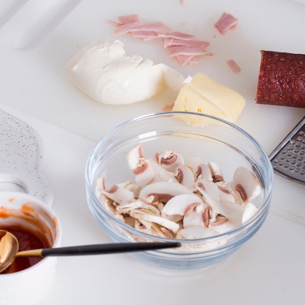 Ломтики грибов; сыр; сливочное масло; ветчина; соус и салями на разделочной доске