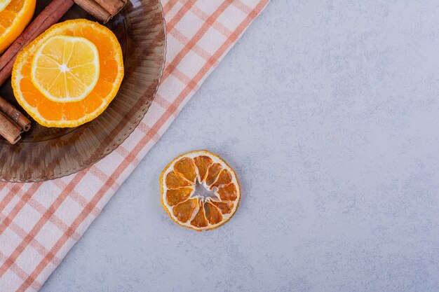 Slices of orange and lemon in glass bowl with cinnamon sticks. 