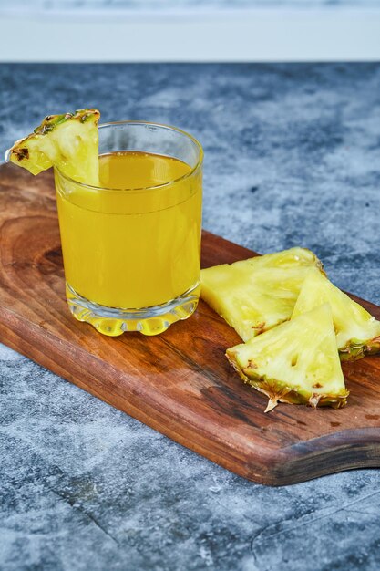 Slices of pineapple and pineapple juice on wooden board.