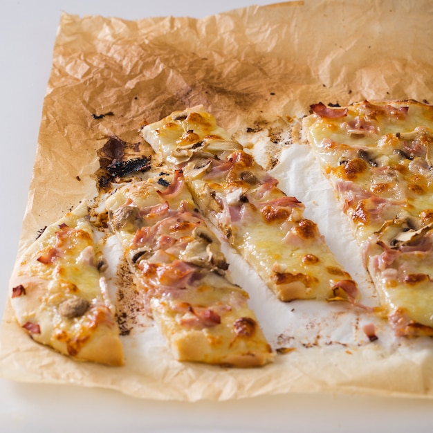 Free photo slices of pizza on parchment paper against white backdrop