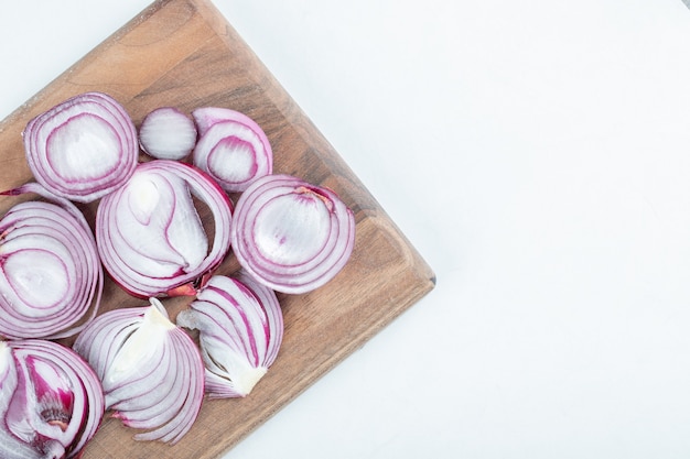 Slices of purple onion on wooden board.