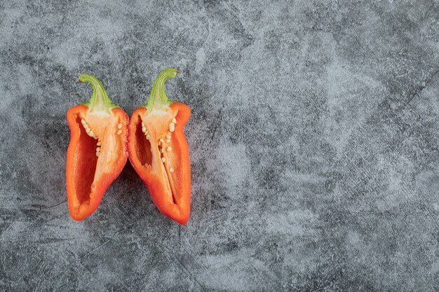 Slices of red pepper on a gray background.