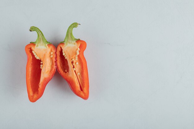 Slices of red pepper on a gray background.