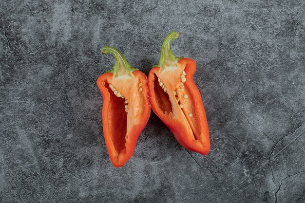 Slices of red pepper on a gray background.