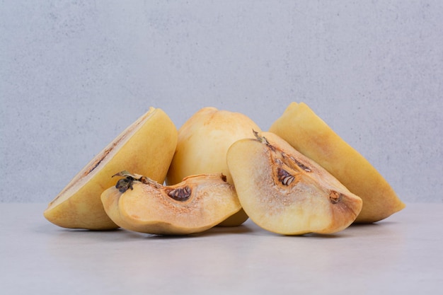 Free photo slices of ripe quince on white table.