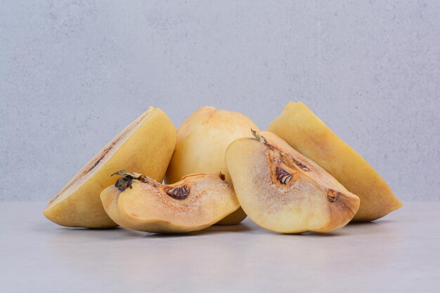 Slices of ripe quince on white table.