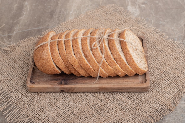 Slices of rye bread on wooden plate with burlap. High quality photo