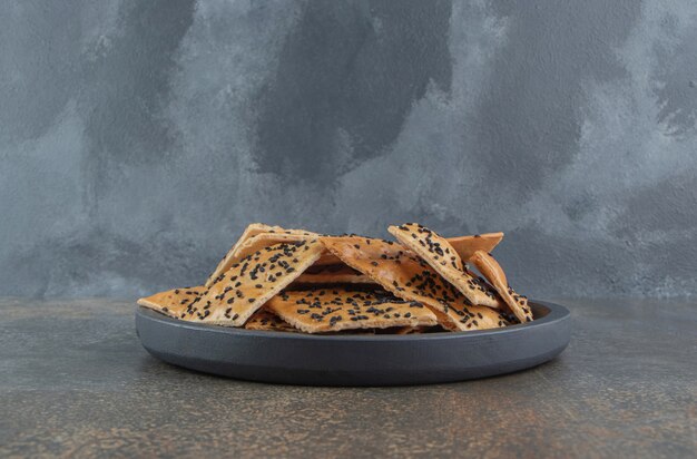 Slices of sesame coated bread piled in a small serving pan 