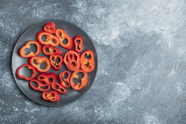 Slices of sweet red peppers on black plate.