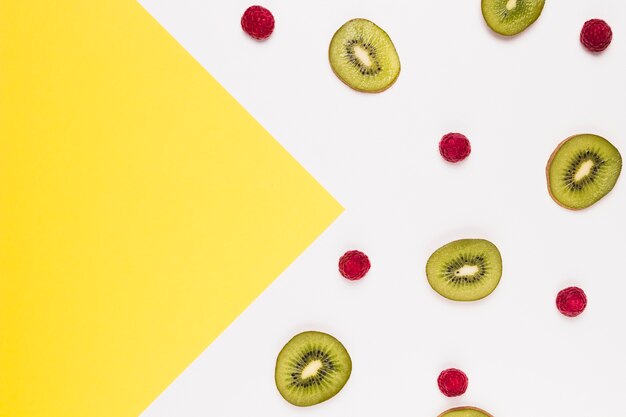 Slices of tasty kiwi and raspberry on multicolored background