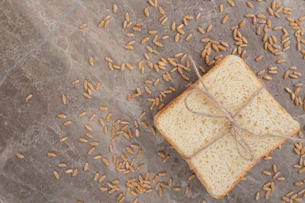 Ломтики тостового хлеба с зернами на мраморной поверхности. Фото высокого качества