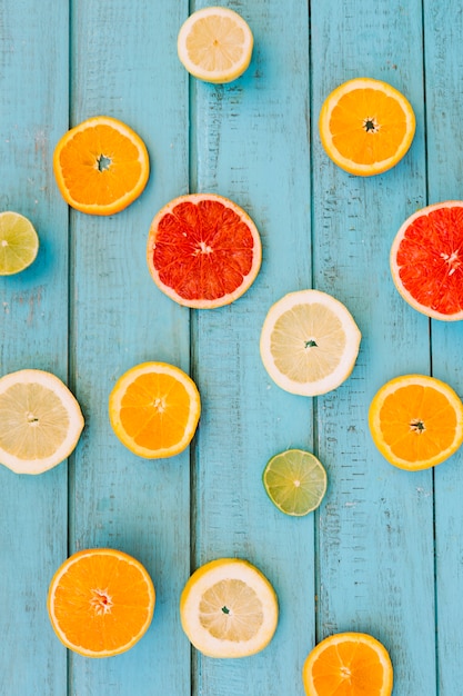 Slices of various juicy citrus fruits on wooden backdrop