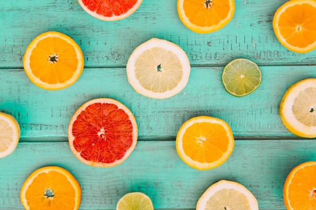 Slices of various juicy citrus fruits on wooden table top