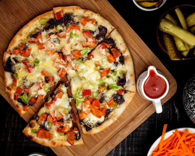 ломтики вегетарианской пиццы с базиликом, помидорами и перцем на деревянном подносе
