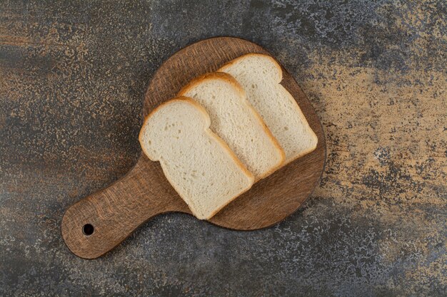 Slices of white toast bread on wooden cutting board.