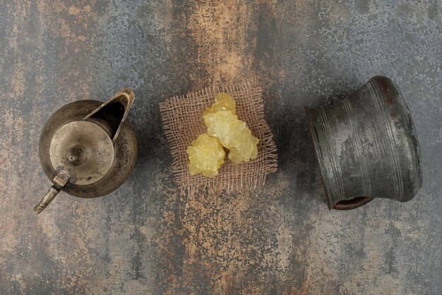 Slices of yellow sweeet sugar with two ancient kettles on marble wall