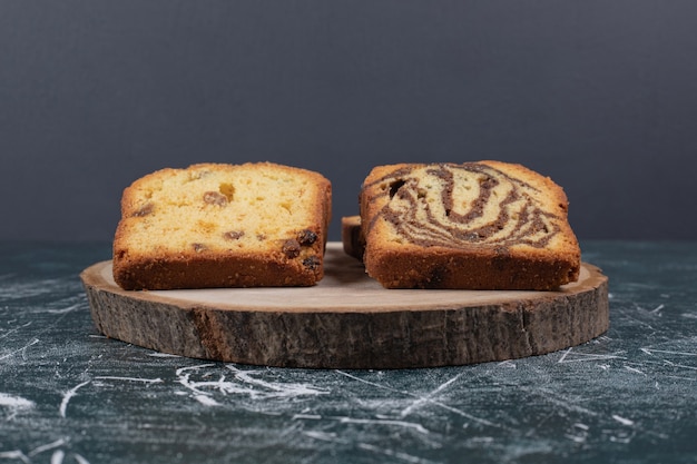 Slices of zebra and raisins cakes on marble table.