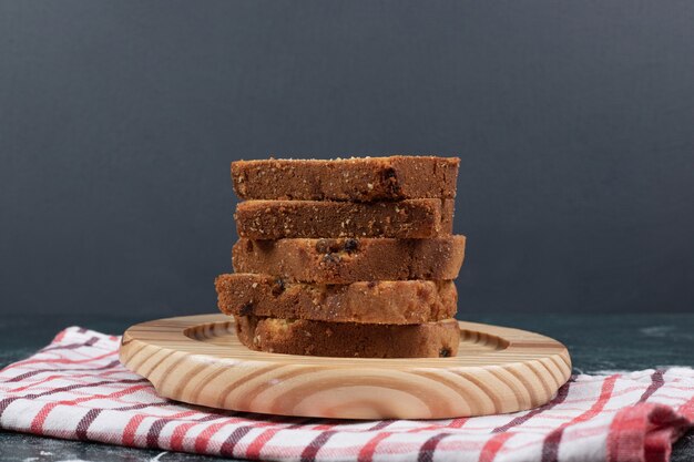 Slices of zebra and raisins cakes on wooden plate.