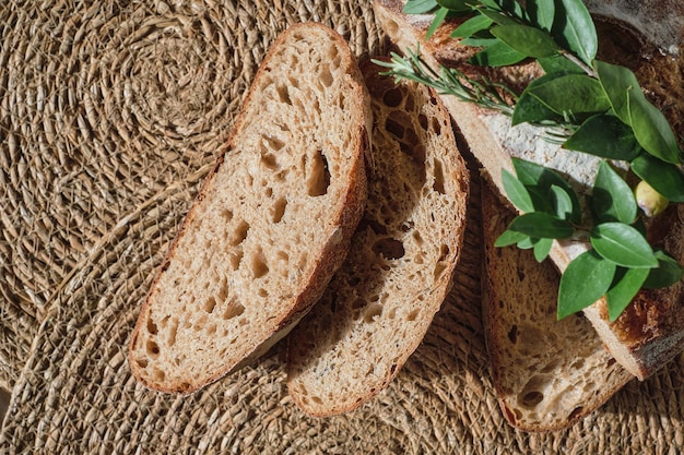 Slicing artisan bread on a straw lining top view Pieces of fresh homemade sourdough bread healthy healthy cuisine