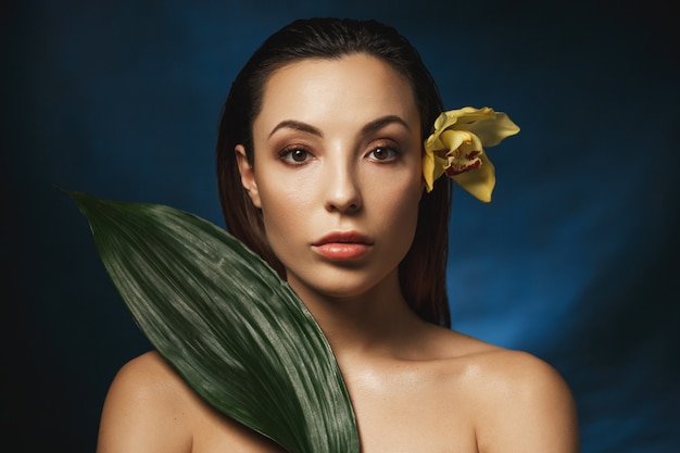 Slicked back hair hairstyle. Attractive woman with flower behind ear.