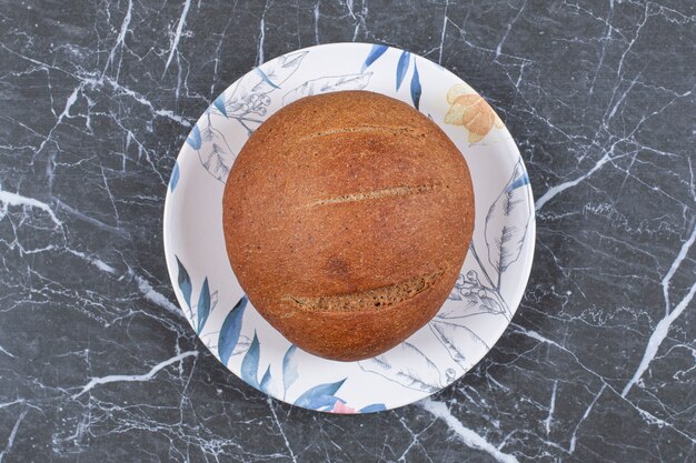 Slight bread loaf on the plate , on the marble surface