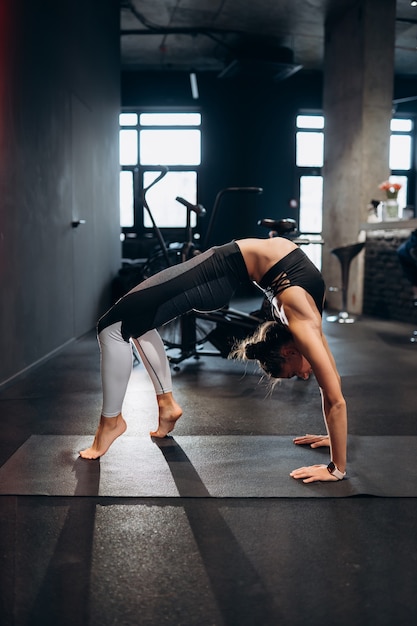 Foto gratuita slim donna atletica che allunga la schiena, facendo esercizio di ponte in palestra