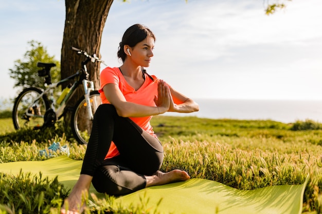 Slim beautiful woman doing sports in morning in park doing yoga