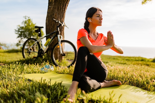 Slim beautiful woman doing sports in morning in park doing yoga