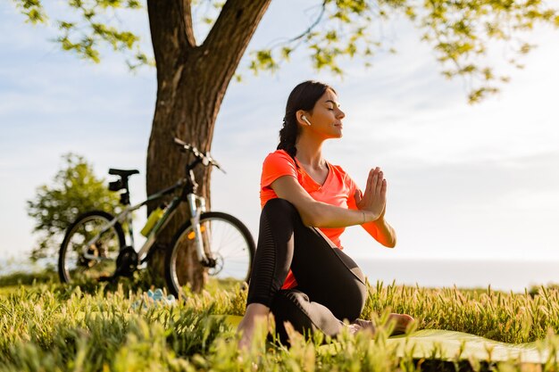 Slim beautiful woman doing sports in morning in park doing yoga