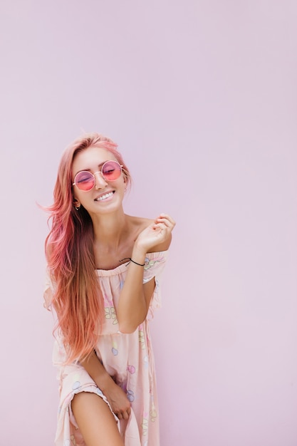 Стройная красивая женщина с длинными розовыми волосами с нежной улыбкой.