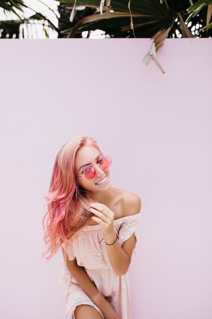 Стройная красивая женщина с длинными розовыми волосами с нежной улыбкой.