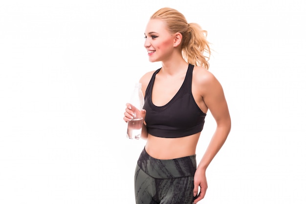 Стройная блондинка пьет воду в тормозах во время фитнес-тренировки