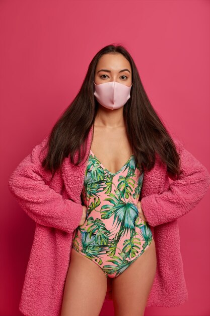 Slim brunette Asian woman wears medical mask to prevent herself from virus