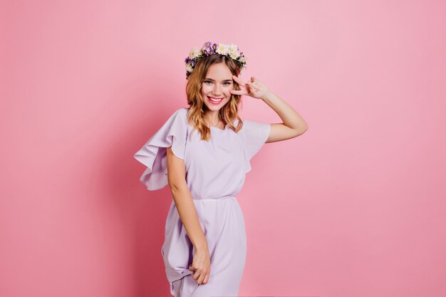 Slim cheerful woman expressing happiness while posing with peace sign