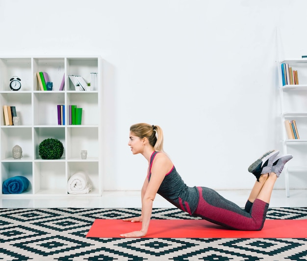 Slim fit young woman doing exercise on red exercise mat