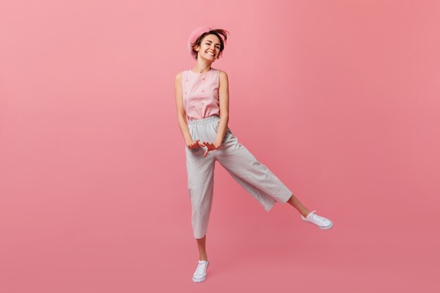 Slim french woman funny dancing on pink wall