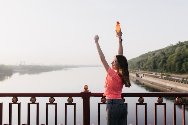 Free photo slim lady in sport uniform enjoying life. portrait from back of european girl looking at sky after training.