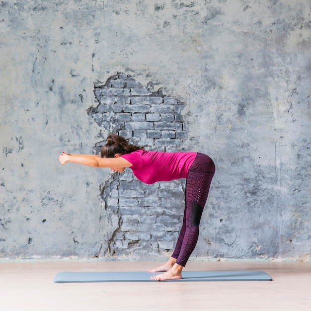 Slim woman doing fitness exercise against weathered grey wall