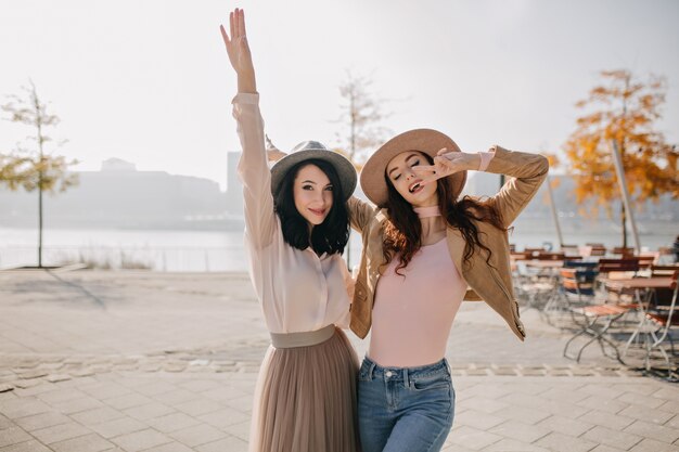 Slim woman in white blouse having fun with best friend