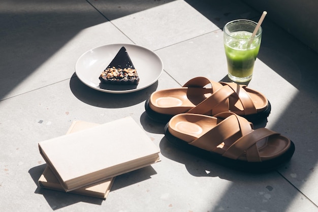 Slippers lemonade piece of cake and books on tiles by the pool