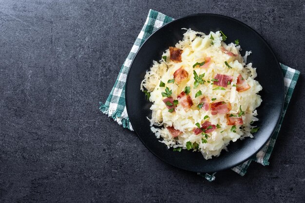 Free photo slovak potato dumplings halusky with steamed sauerkraut and bacon on black background